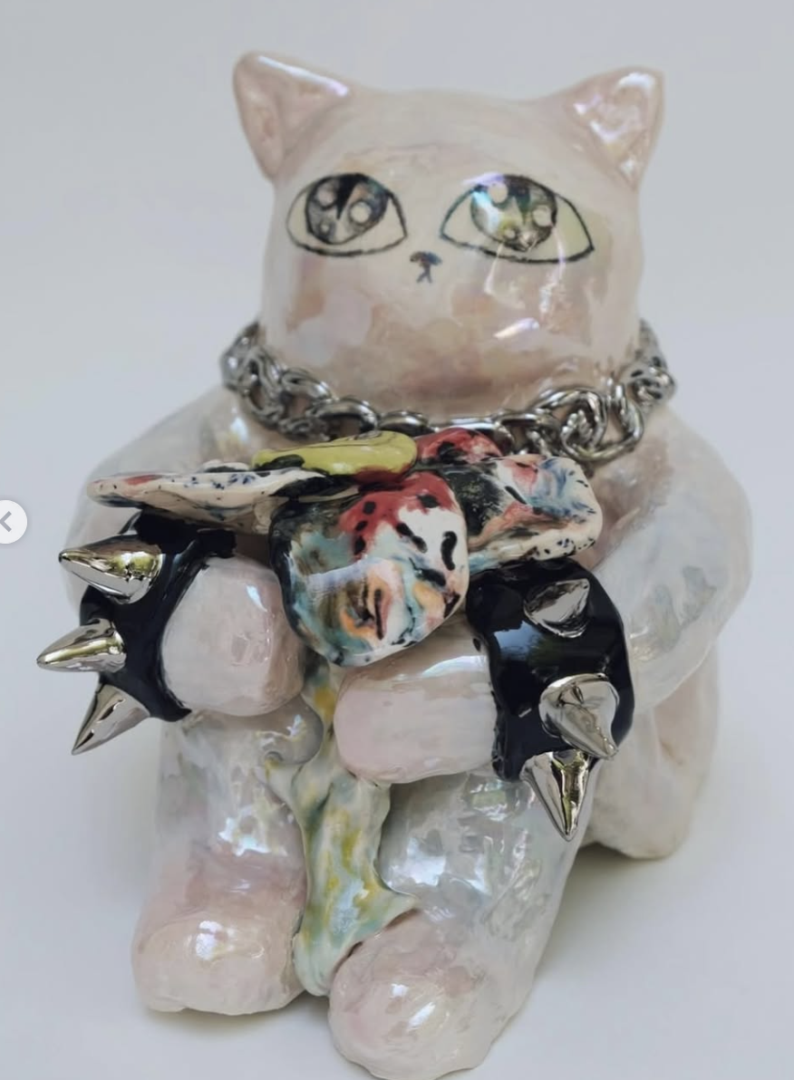 Ceramic cat figure holding a colorful spiked object