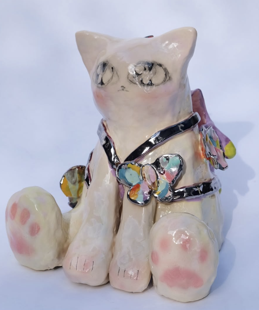 Ceramic cat figure with colorful butterflies and pink paws