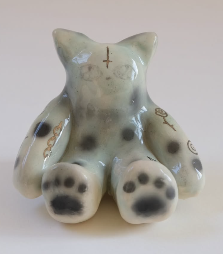 Small pale green ceramic cat figure with spotted paws