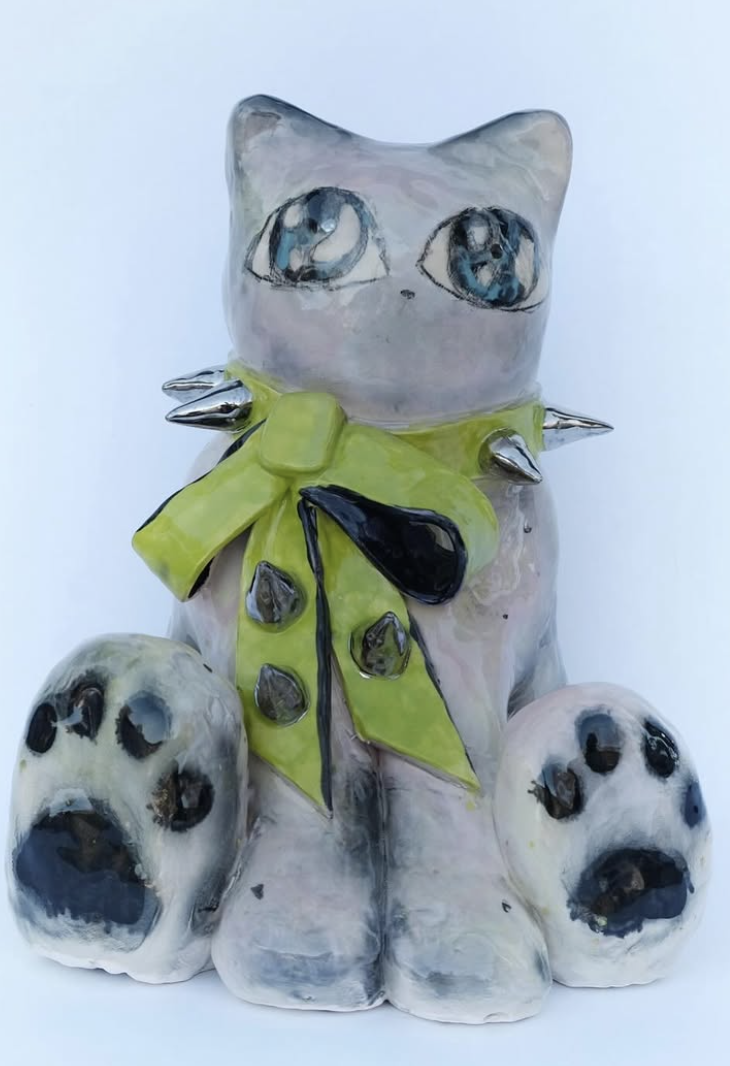 Ceramic cat figure with lime bow and large paws