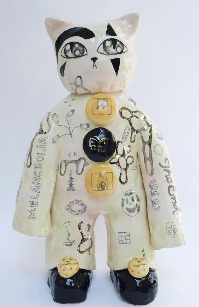 Ceramic cat figure with painted drawings and yellow buttons