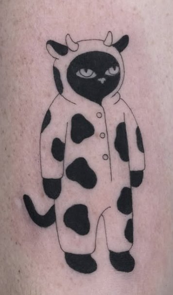 Fine-line tattoo of a cat in a cow-print onesie
