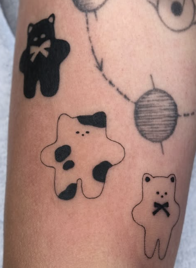 Linework tattoo of small plush cats with a yarn ball