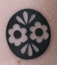 Blackwork tattoo of flowers inside a circle