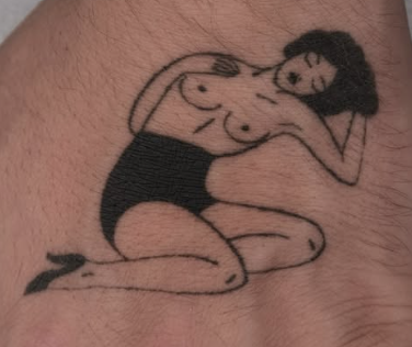 Linework tattoo of a reclining pinup figure in black shorts