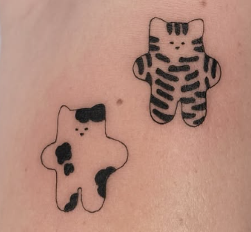 Linework tattoo of two small plush cats