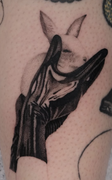 Shaded tattoo of a bunny held by a black gloved hand